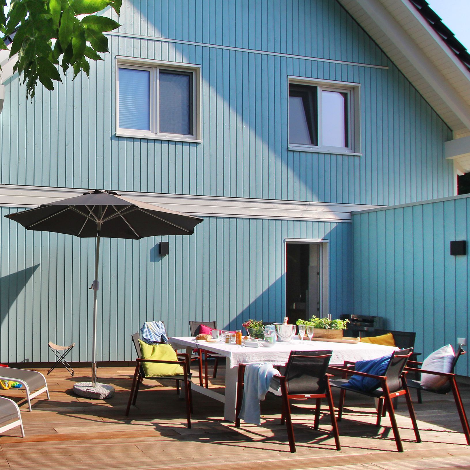 Terasse mit Sonennschirm und Gartenmöbeln hinter Ferienhaus Ribe