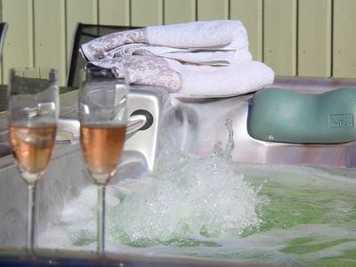 Zwei gefüllte Sektgläser vor laufendem Jacuzzi, weiter hinten liegen Handtücher
