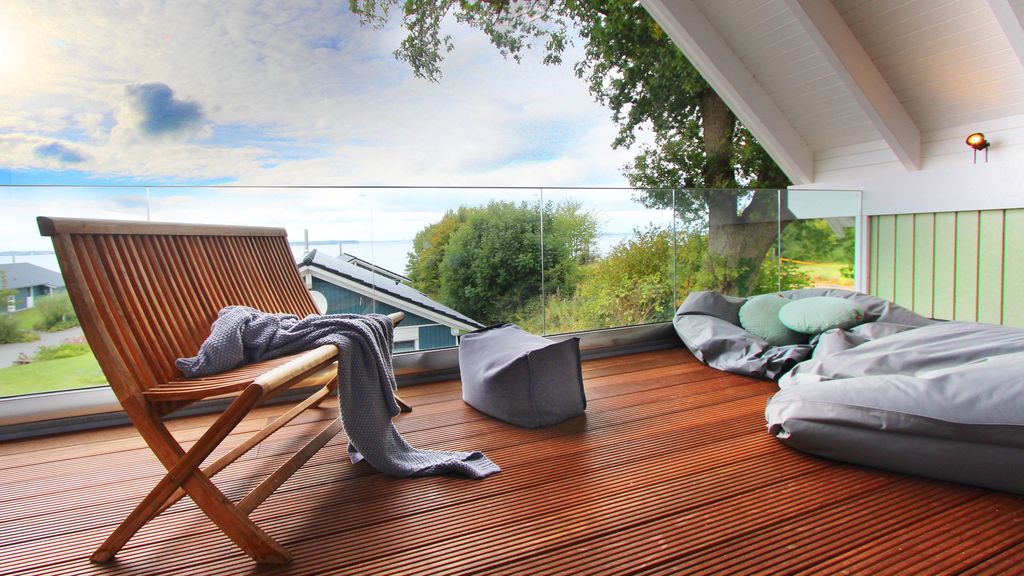 Balkon vom Ferienhaus Vajle mit Holzbank, Kissen, Sitzsäcken und Aussichtauf das Gelände und den Strand