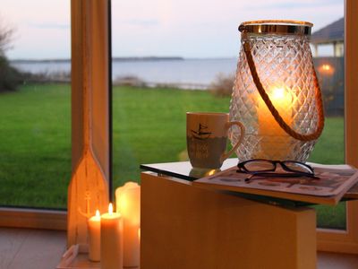 Rechts Beistelltisch mit Kerze, Brille und Glas mit Kerze, Hintergrund Fenster udn Kerzen